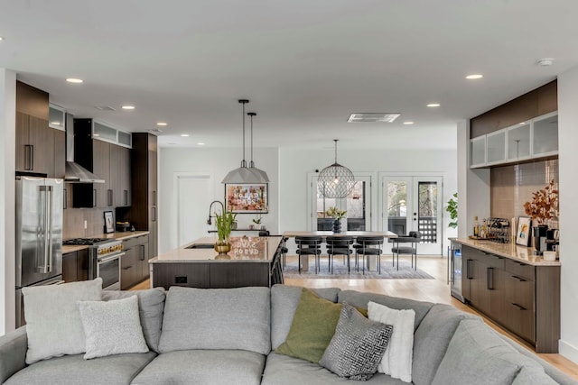 living room featuring french doors, sink, and light hardwood / wood-style flooring