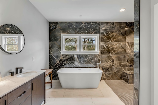 bathroom featuring vanity, a tub, and tile walls