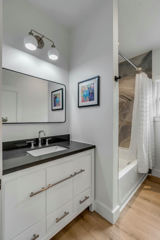 bathroom with shower / tub combo with curtain, hardwood / wood-style floors, and vanity