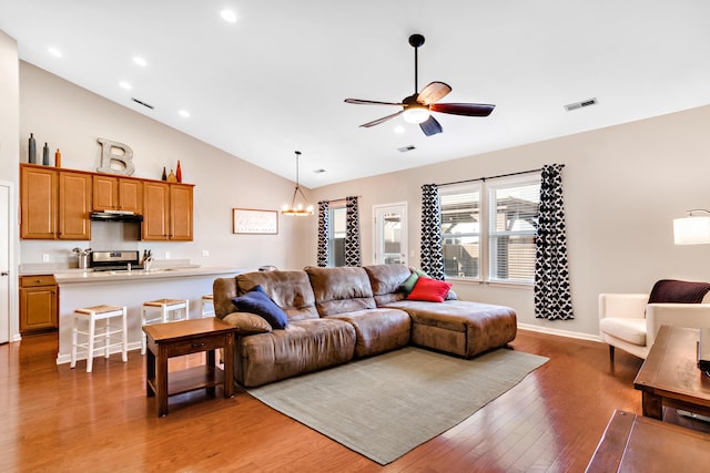 living room with hardwood / wood-style floors, ceiling fan with notable chandelier, and lofted ceiling