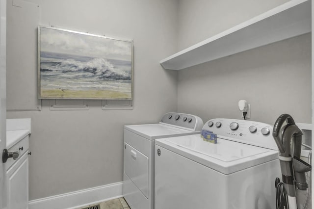 laundry room featuring cabinets, light tile patterned floors, and washer and dryer