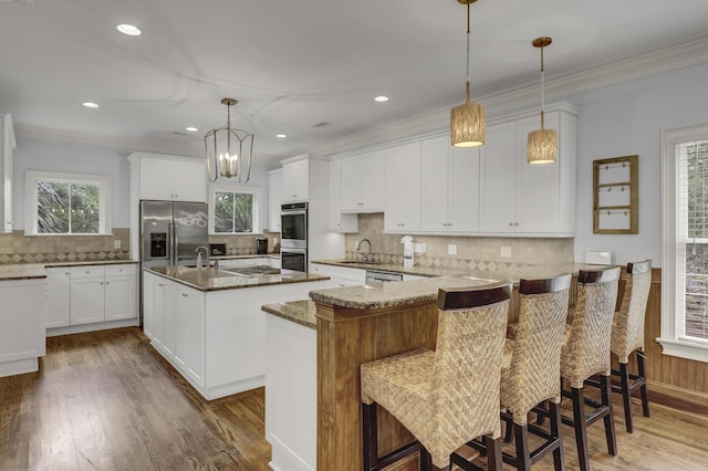 kitchen featuring appliances with stainless steel finishes, a kitchen island with sink, sink, dark stone countertops, and white cabinetry