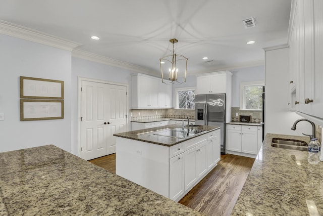 kitchen featuring a center island with sink, white cabinets, dark stone counters, and sink