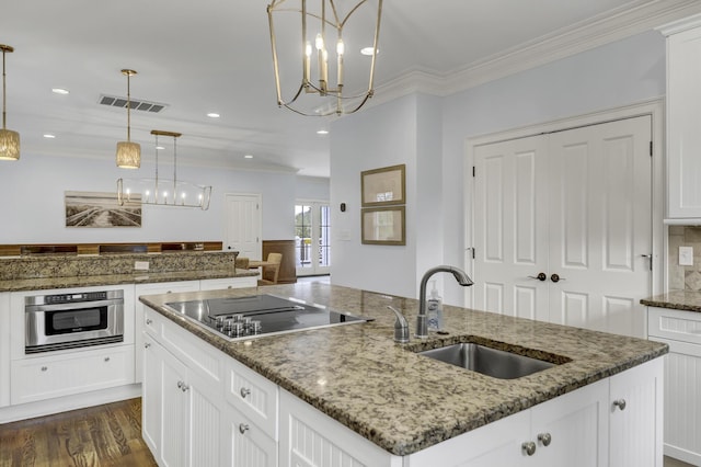 kitchen with a center island with sink, oven, hanging light fixtures, dark stone countertops, and black electric cooktop