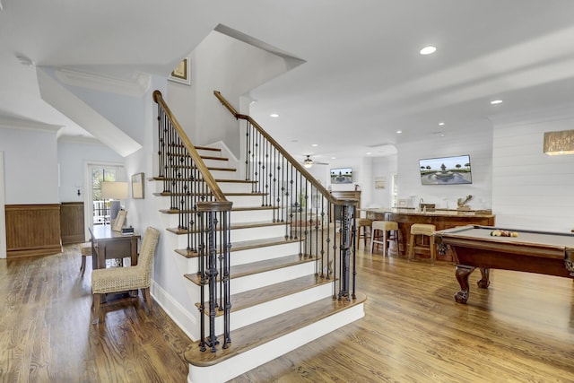 staircase featuring wood-type flooring, ceiling fan, crown molding, and billiards