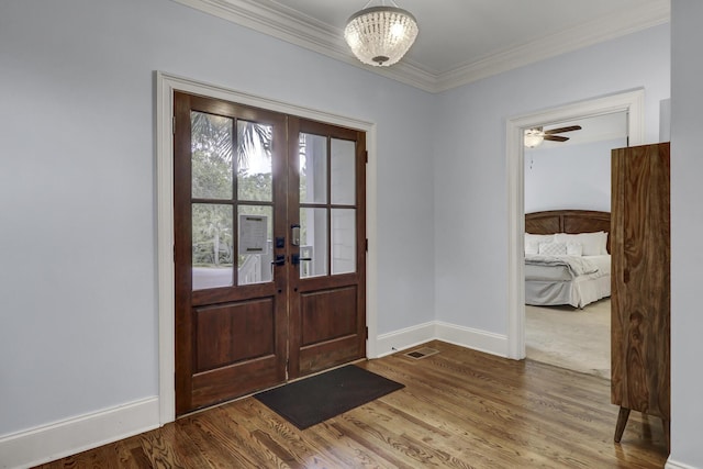 entryway featuring hardwood / wood-style floors, ceiling fan with notable chandelier, ornamental molding, and french doors