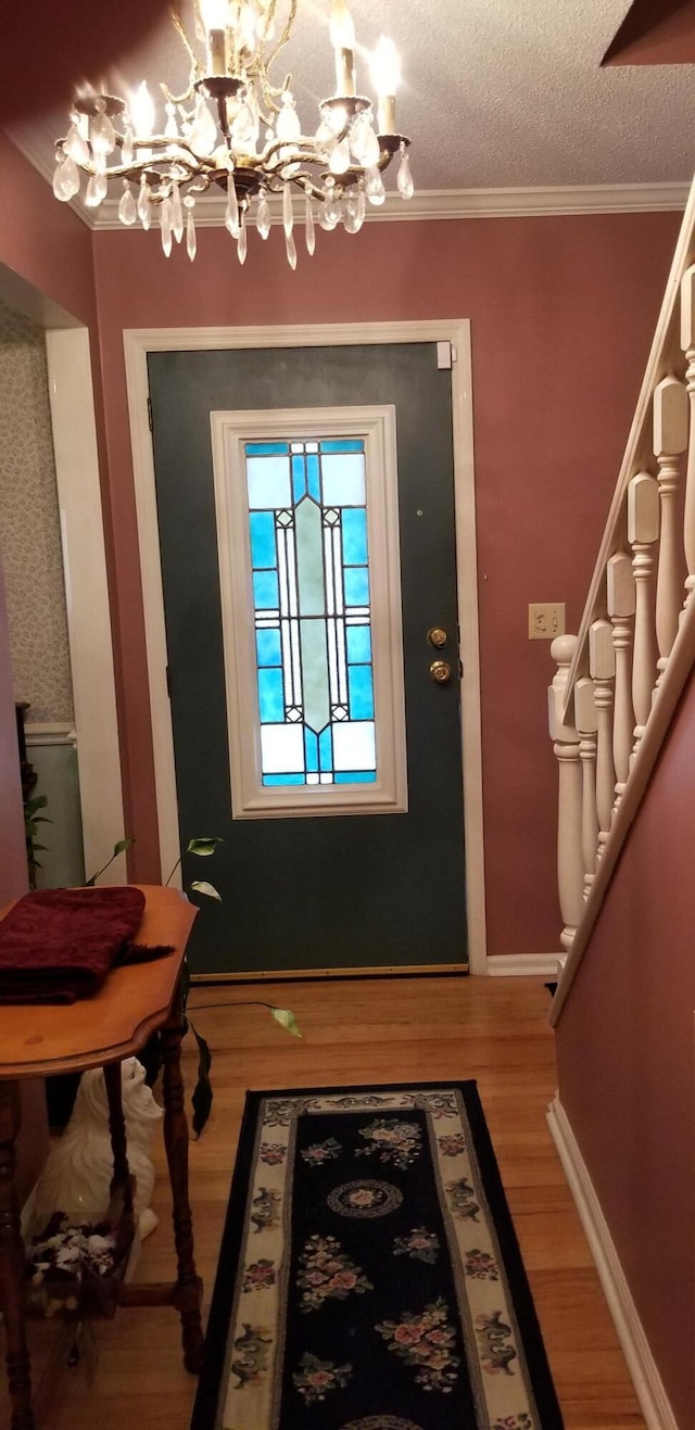 doorway to outside featuring hardwood / wood-style flooring, a notable chandelier, ornamental molding, and a textured ceiling