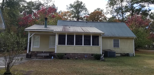 back of house with central AC unit, a sunroom, and a yard