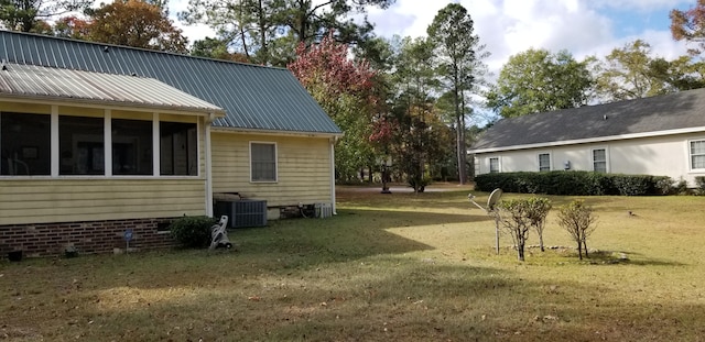 view of side of home featuring a lawn, a sunroom, and cooling unit