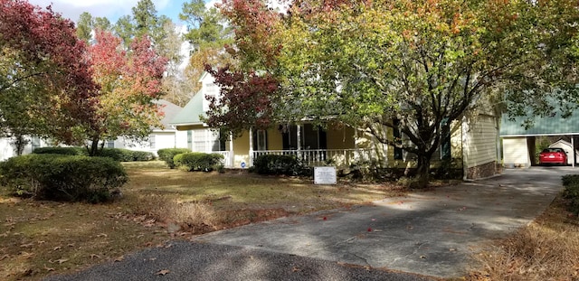 view of property hidden behind natural elements with covered porch and a carport