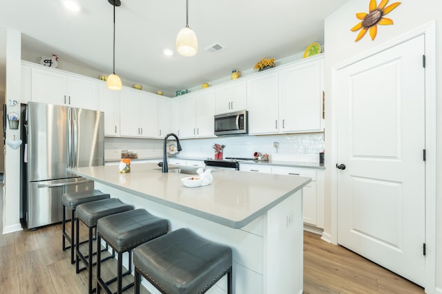 kitchen with light wood-type flooring, pendant lighting, stainless steel appliances, and white cabinets