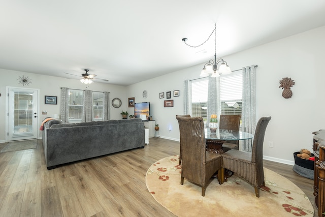 dining room featuring ceiling fan with notable chandelier and light wood-type flooring