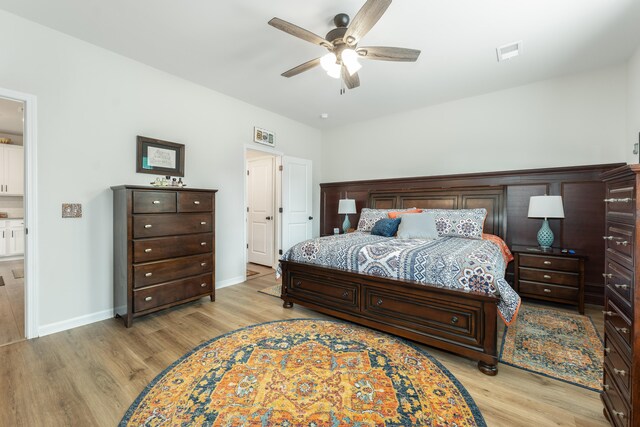 bedroom with light wood-type flooring, ensuite bath, and ceiling fan