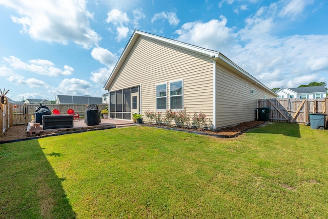 rear view of property with a lawn, a sunroom, and a patio