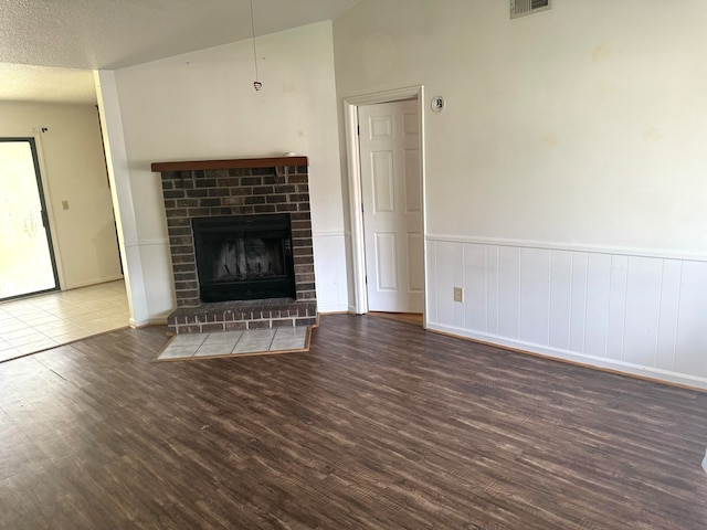 unfurnished living room with a textured ceiling, wood-type flooring, and a fireplace