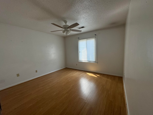 spare room with ceiling fan, wood-type flooring, and a textured ceiling