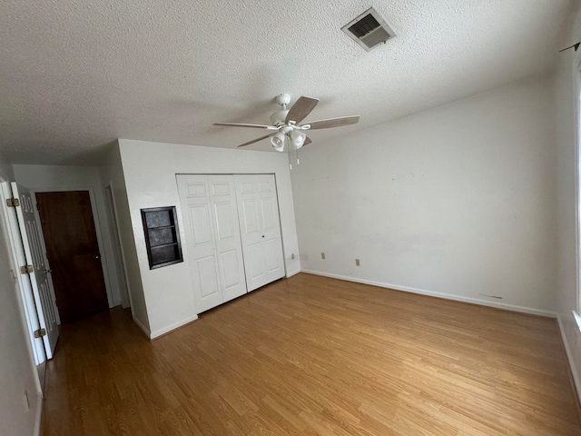 unfurnished bedroom featuring a closet, ceiling fan, hardwood / wood-style floors, and a textured ceiling