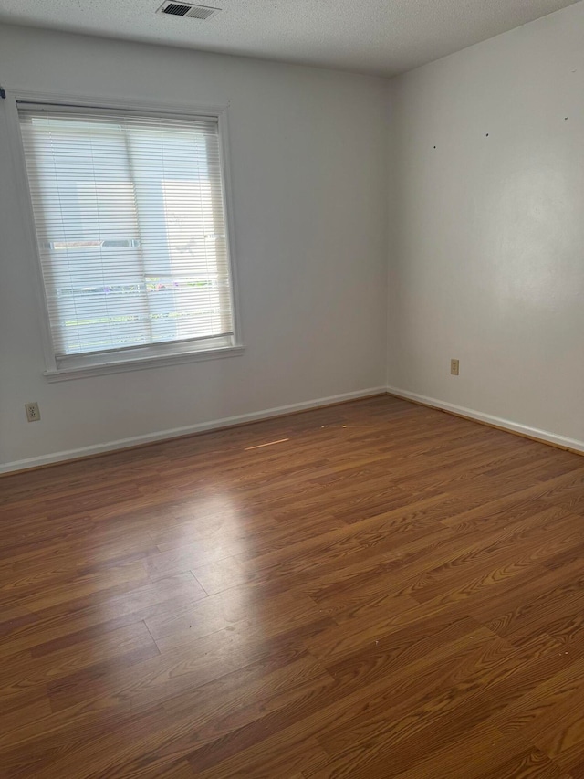 spare room featuring dark hardwood / wood-style flooring and a textured ceiling