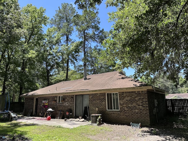 rear view of house with cooling unit, a patio area, and a trampoline