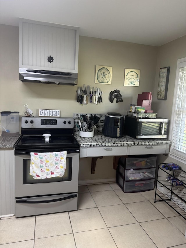 kitchen featuring appliances with stainless steel finishes, exhaust hood, and light tile patterned flooring