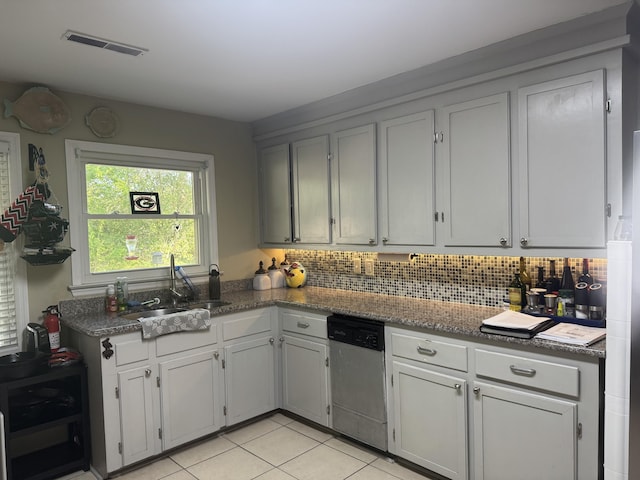 kitchen featuring tasteful backsplash, visible vents, light tile patterned floors, dishwasher, and a sink