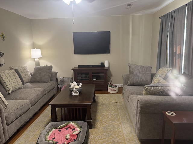 living area with visible vents, ceiling fan, and wood finished floors