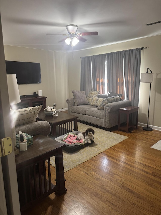 living area with ceiling fan, baseboards, visible vents, and wood finished floors