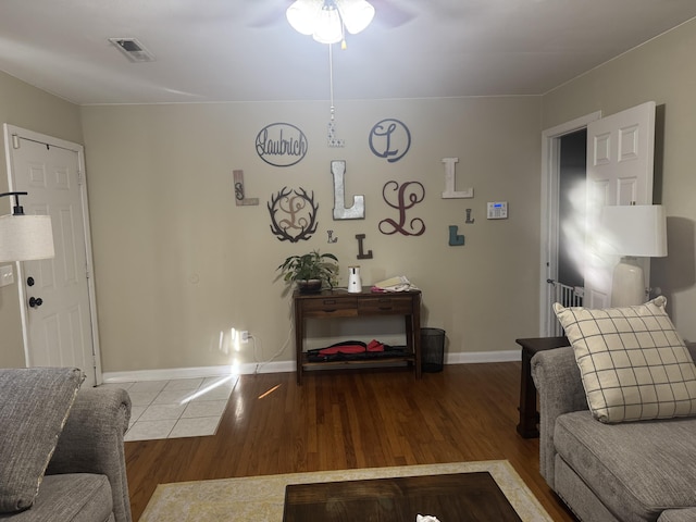 living area with wood finished floors, baseboards, a ceiling fan, and visible vents