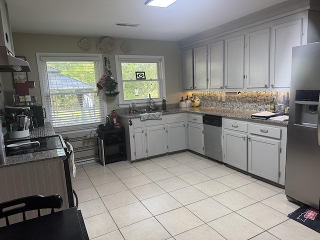kitchen with dark stone countertops, light tile patterned floors, ventilation hood, stainless steel appliances, and backsplash