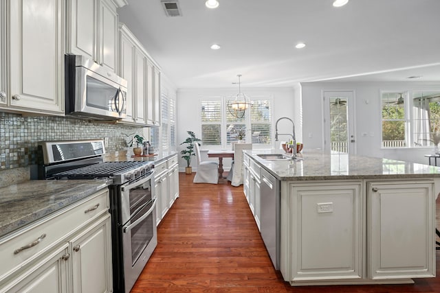 kitchen with dark wood-type flooring, an island with sink, white cabinets, and appliances with stainless steel finishes