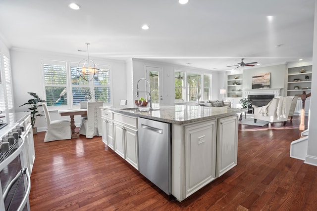 kitchen with dark wood-type flooring, decorative light fixtures, sink, an island with sink, and appliances with stainless steel finishes