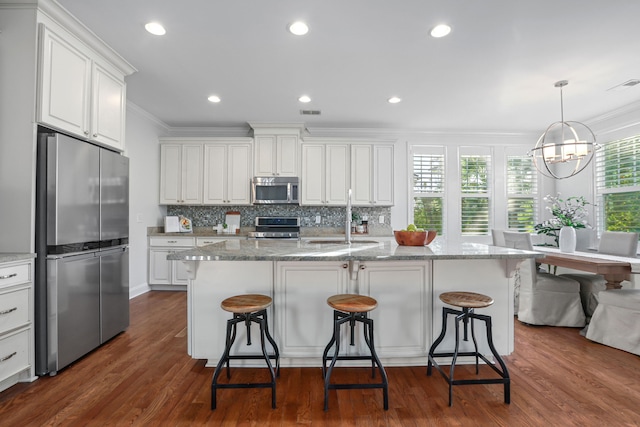 kitchen with stainless steel appliances, plenty of natural light, dark hardwood / wood-style floors, and a center island with sink