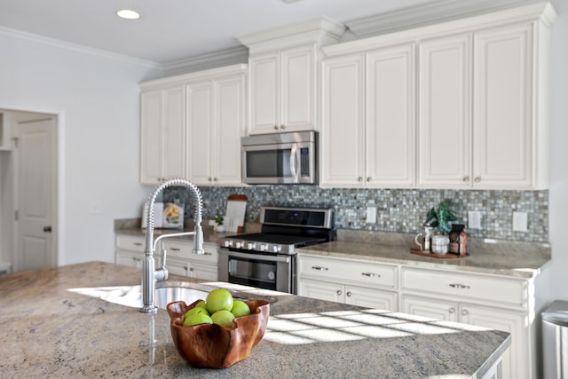 kitchen with light stone counters, white cabinets, appliances with stainless steel finishes, and crown molding