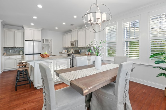 dining room featuring ornamental molding, sink, a chandelier, and dark hardwood / wood-style floors