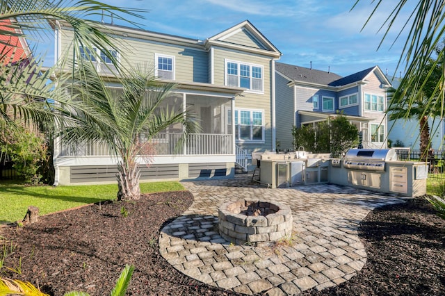 rear view of house featuring an outdoor fire pit, a patio area, a sunroom, and area for grilling