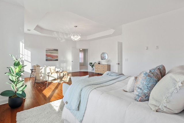 bedroom featuring hardwood / wood-style floors, a chandelier, and a raised ceiling