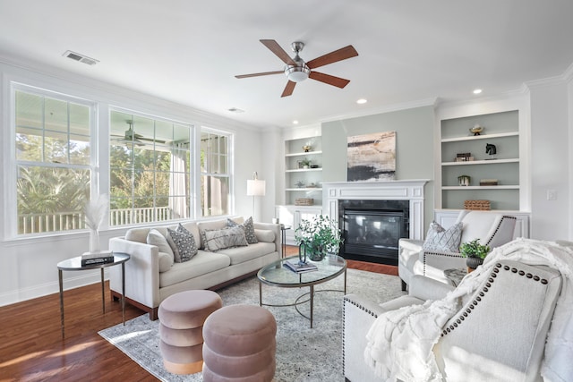 living room with ornamental molding, ceiling fan, built in shelves, and hardwood / wood-style floors