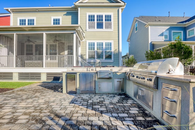 back of property featuring an outdoor kitchen, a sunroom, ceiling fan, and a patio