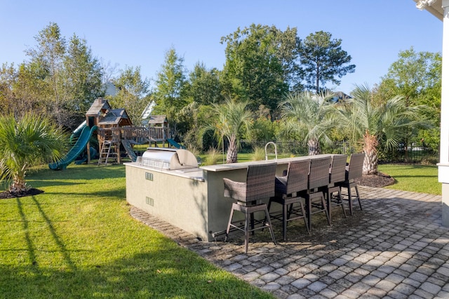 view of patio / terrace with a playground, an outdoor bar, and an outdoor kitchen