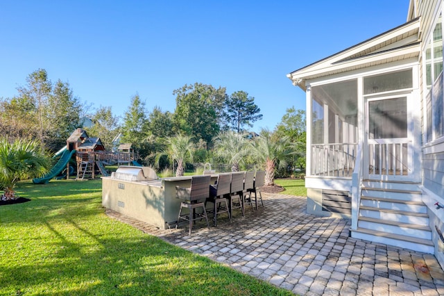 view of yard featuring an outdoor bar, a sunroom, a playground, and a patio area