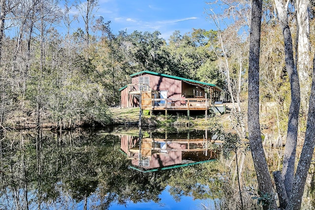 back of house featuring a wooded view and a deck with water view