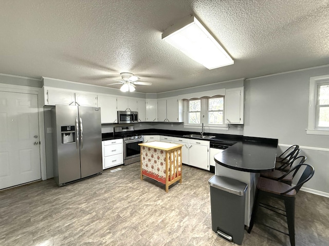 kitchen featuring appliances with stainless steel finishes, kitchen peninsula, sink, and white cabinets