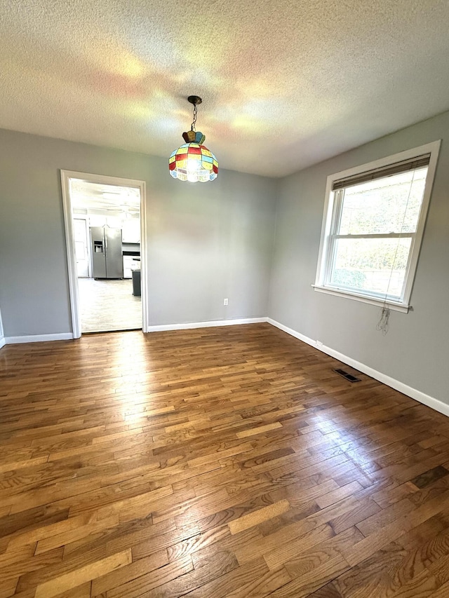 unfurnished dining area featuring dark wood-type flooring and a textured ceiling