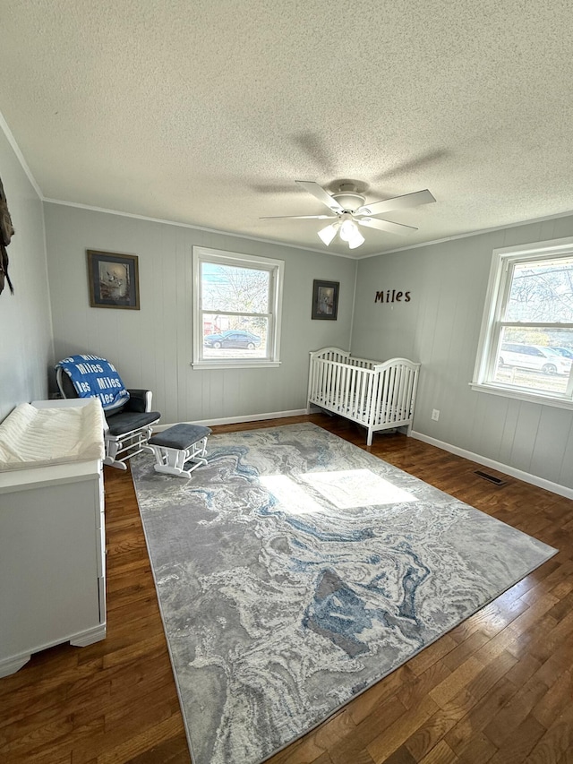 bedroom with multiple windows, a textured ceiling, dark hardwood / wood-style floors, and ceiling fan