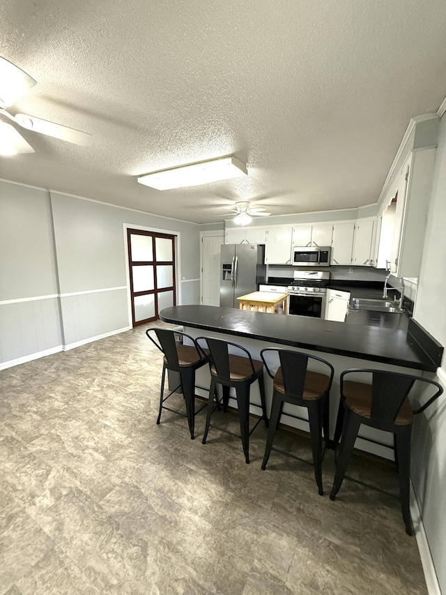 kitchen with sink, white cabinetry, kitchen peninsula, ceiling fan, and stainless steel appliances