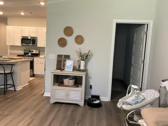 305 Camellia Bloom Dr, Moncks Corner, SC 29461 - kitchen featuring stainless steel appliances, wood finished floors, a kitchen bar, baseboards, and white cabinetry