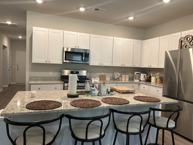 305 Camellia Bloom Dr, Moncks Corner, SC 29461 - kitchen featuring appliances with stainless steel finishes, dark wood-type flooring, white cabinetry, and a breakfast bar area