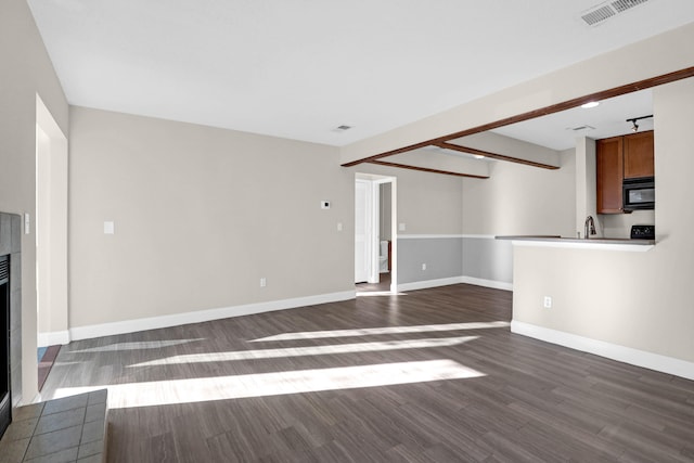 unfurnished living room featuring sink and dark hardwood / wood-style floors