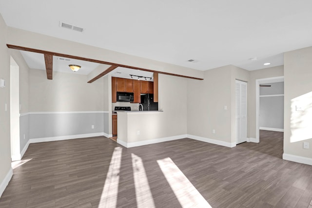 unfurnished living room featuring beam ceiling and dark wood-type flooring