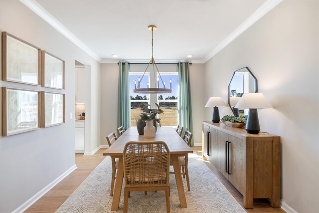 dining area with a notable chandelier, crown molding, a healthy amount of sunlight, and light hardwood / wood-style floors